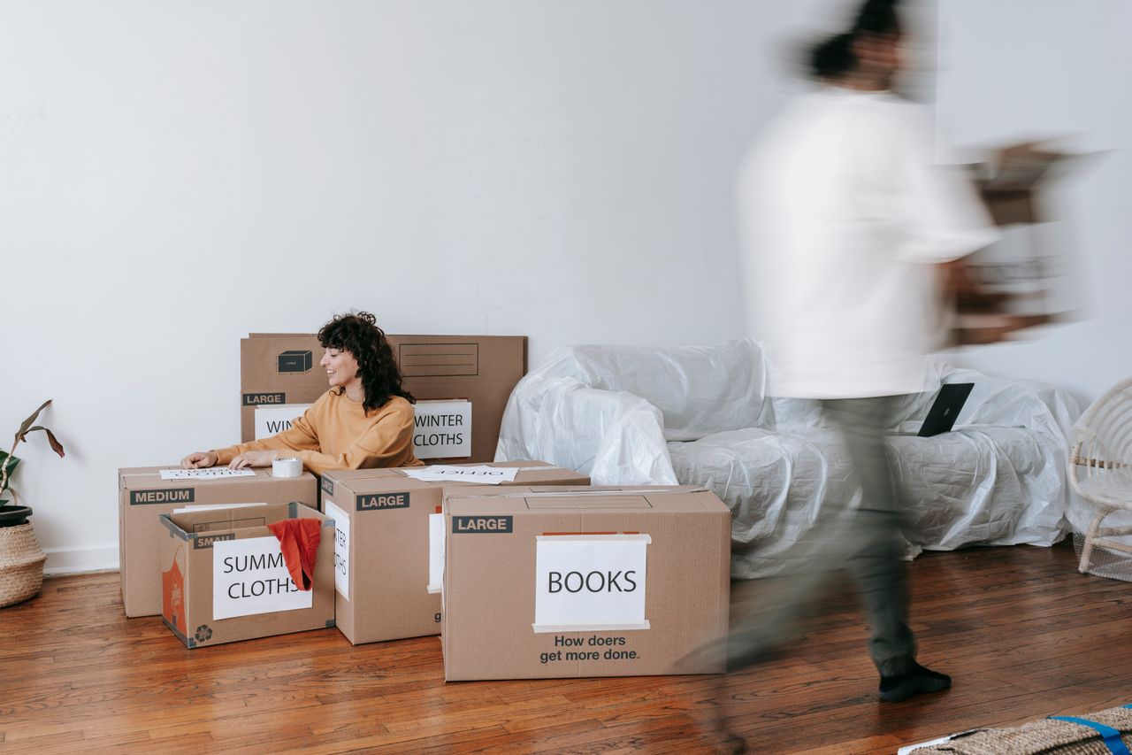 Un couple range des cartons étiquetés dans un salon minimaliste, en vue du jour du déménagement.